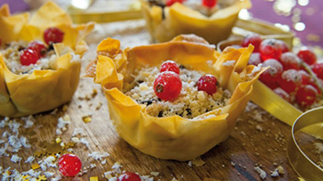 Snowy mince pies served on a chopping board surrounded by fake snow and gold glitter