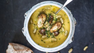 Boxing Day Soup served in a grand silver dish with a spoon topped with chives with a crusty bread roll on the side