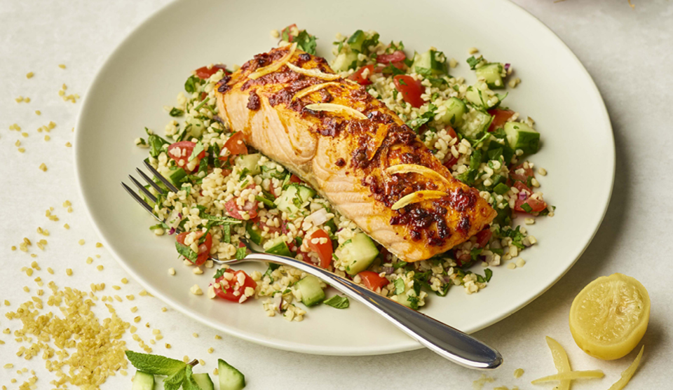 Harissa Salmon with Herby Tabbouleh served on a white plate with a lemon wedge on the side