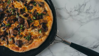 Northern Dough Co Creamy Mushroom and Garlic Pizza with Fresh herbs served on a black plate