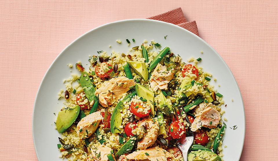 Herby Salmon and Cous Cous Salad served on a white plate, on top of a white table cloth