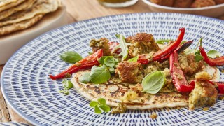 Spelt Pancakes with Falafels on a blue and white plate, topped with roasted red peppers and basil