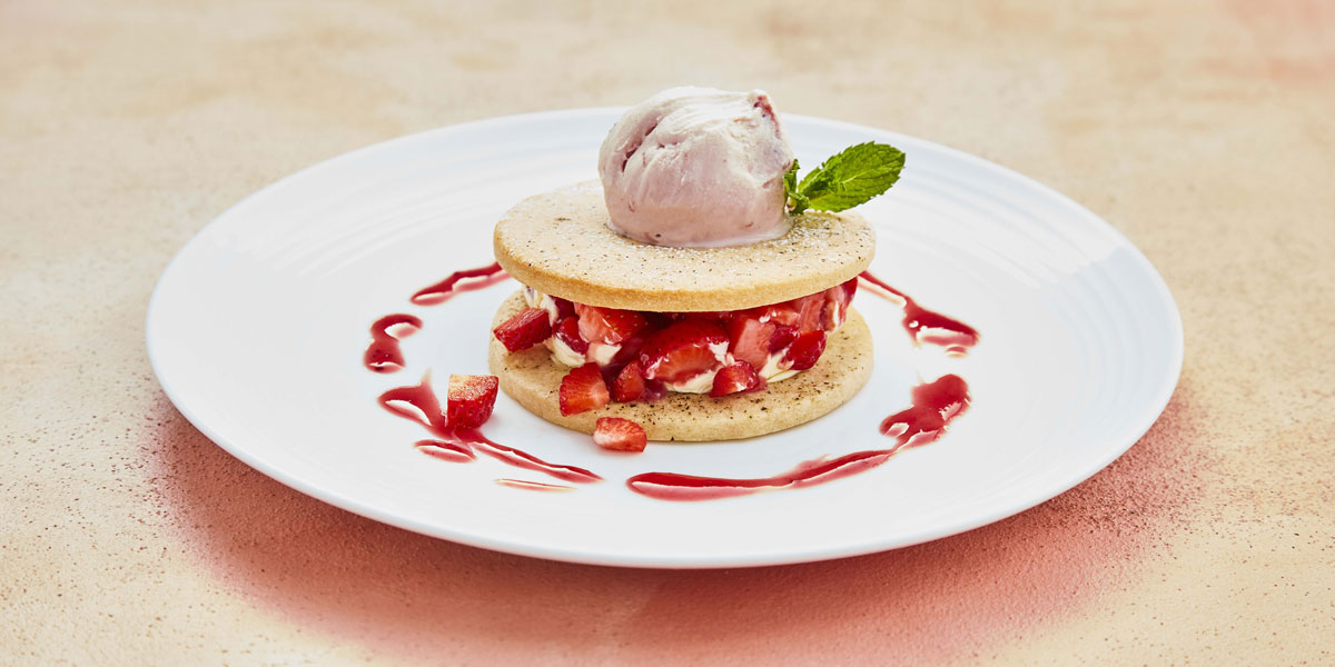 Black Pepper Strawberry Shortbread Sandwich served on a white plate, topped with ice cream with strawberry sauce drizzled