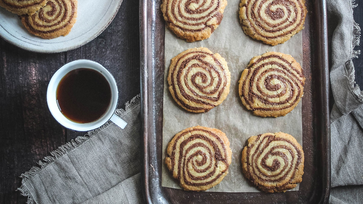 Pinwheel Shortbreads served on parchment paper and on a baking tray next to a cup of tea