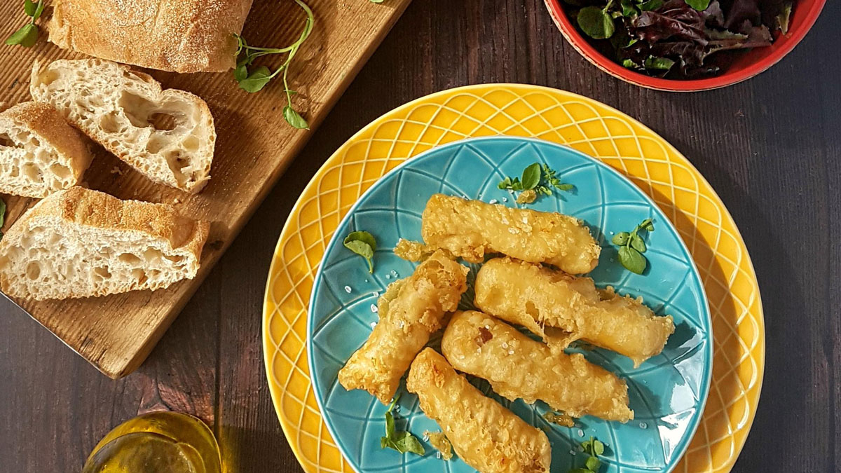 Lightly Spiced Fish Goujons served on a blue plate next to slices of crusty bread