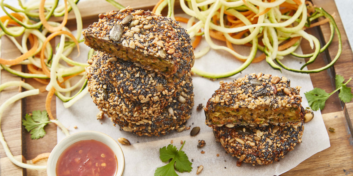 Mini Veggie Sliders served on a wooden boards with spiral cut vegetables and sweet chilli dipping sauce